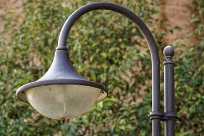 Close-up of electric lamp hanging on metal fence