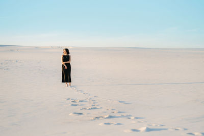 Rear view of woman on beach against sky