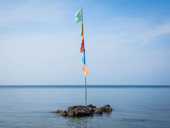 Lifeguard hut on rock in sea against sky