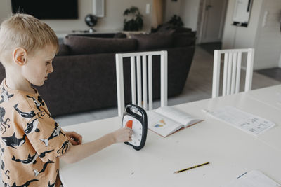 Schoolboy doing homework according to clock
