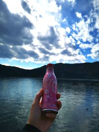 Midsection of person holding water against sky