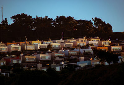 Buildings and trees against clear sky