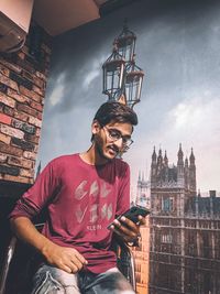 Full length of young man sitting on building in city