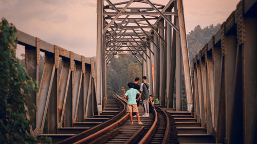 People standing on railway bridge against sky