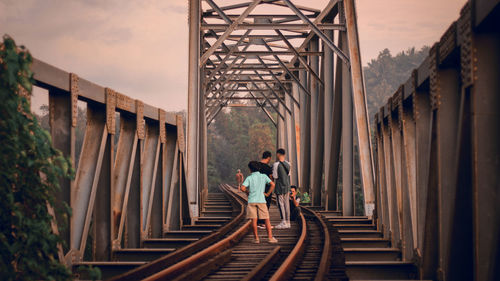 Rear view of men on bridge against sky