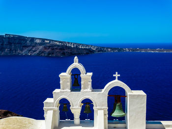 View of building by sea against blue sky