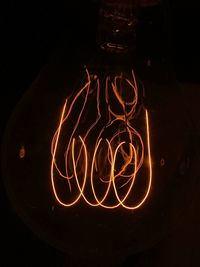 Close-up of illuminated light bulb against black background