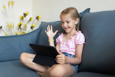 Young woman using mobile phone while sitting on sofa at home