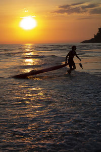 Silhouette man on beach against sky during sunset