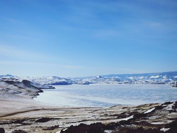 Scenic view of sea and mountains against blue sky