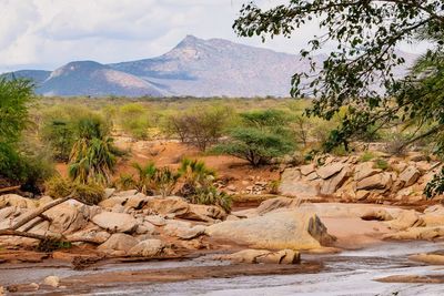 Scenic view of ewaso nyiro river against rocky mountains and sky in samburu national reserve, kenya 