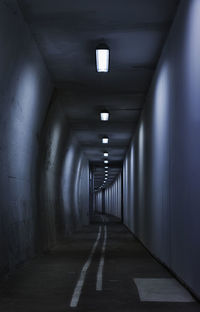 Seamless tunnel lighted by neon tubes , long white lines point the direction 