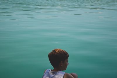Rear view of boy against turquoise lake