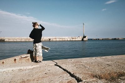 Woman standing on footpath in front of sea