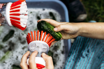 Cropped hands of boy cleaning cucumber with brush