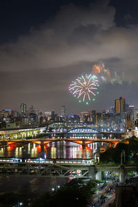 Firework display over river and buildings in city at night