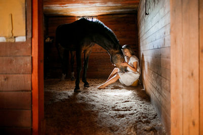 Woman stroking horse in stable