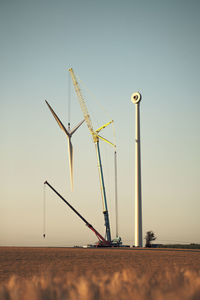 Wind turbines on field against clear sky