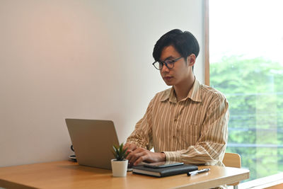 Senior woman using smart phone while sitting on table
