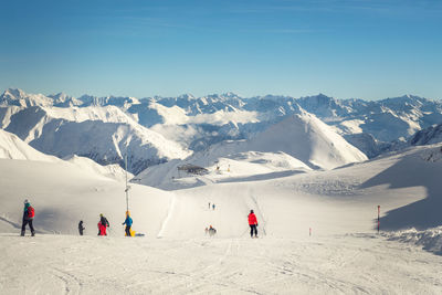 People on snowcapped mountain against sky