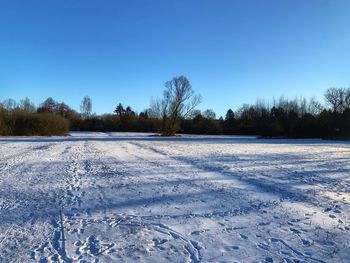 Scenic view of snow field against clear blue sky