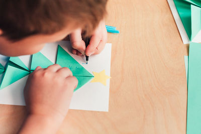 Midsection of boy holding paper with text on table