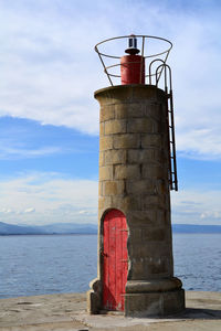 Lighthouse by sea against sky