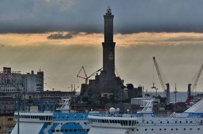 Cranes in city against sky during sunset