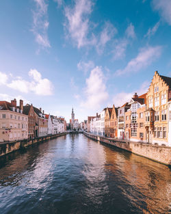 Buildings by river against sky