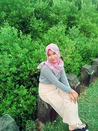 Portrait of young woman standing against plants