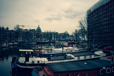 Boats moored at harbor against buildings in city