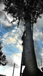 Low angle view of power lines against cloudy sky