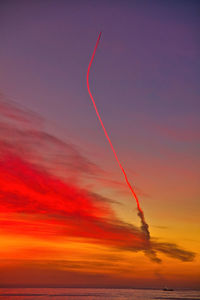 Low angle view of vapor trails in sky during sunset