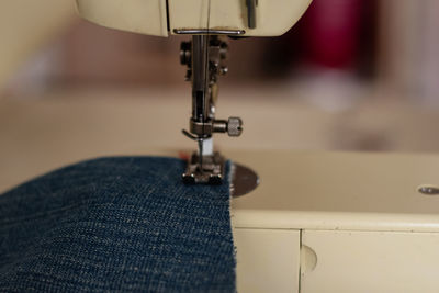 Sewing machine close up sewing blue jeans denim.