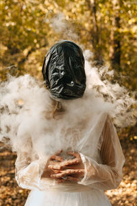 Woman wearing plastic bag in forest