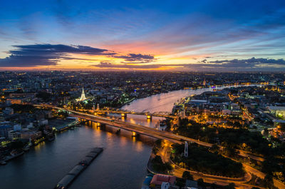 High angle view of illuminated city against sky at sunset