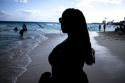 Silhouette woman standing on beach against sky