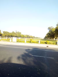 Road by trees against clear sky