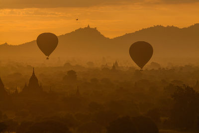 Silhouette of hot air balloons against sky during sunset