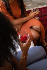 Two women seated and talking with wine glasses in hand 