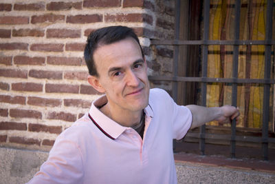 Portrait of young man standing against brick wall