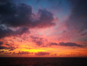 Scenic view of sea against dramatic sky during sunset