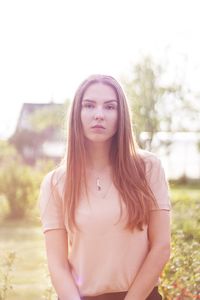 Portrait of young woman standing against tree