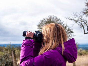 Rear view of woman photographing against sky