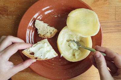 Woman hands speading soft and creamy cheese on a piece of bread. personal point of view