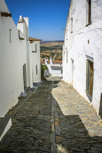 Footpath amidst buildings in town against clear blue sky