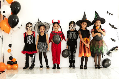 Portrait of friends standing against wall during halloween