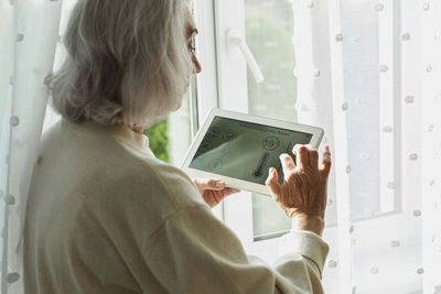 Senior woman adjusting temperature on smart home device