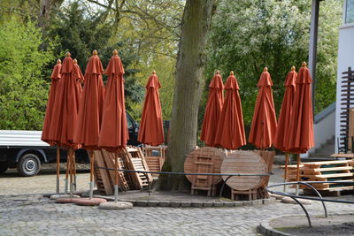 Closed parasols with chairs and table near tree in yard