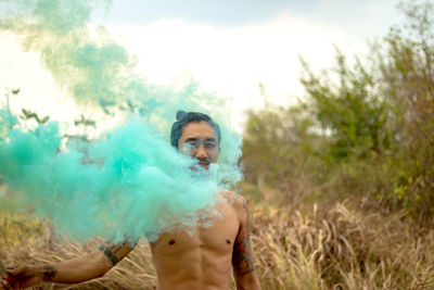 Shirtless man with distress flare standing in forest